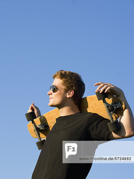 Österreich  Junger Mann mit Skateboard
