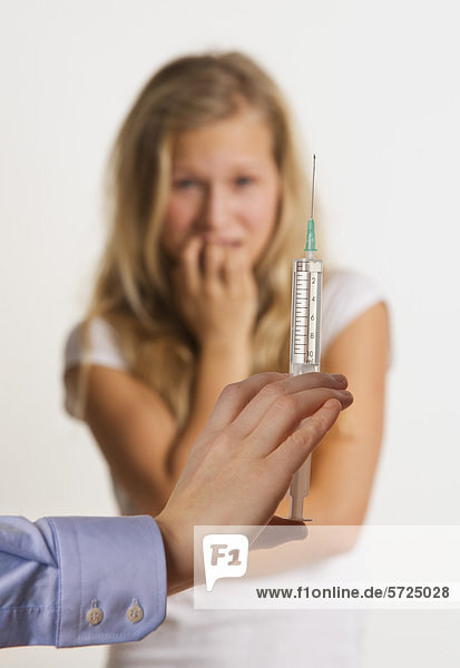 Ärztin mit Injektion  während Teenager-Mädchen im Hintergrund