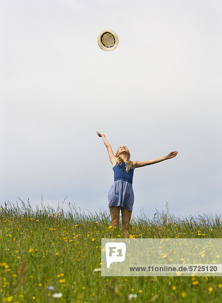 Österreich  Teenagermädchen spielt mit Strohhut im Feld