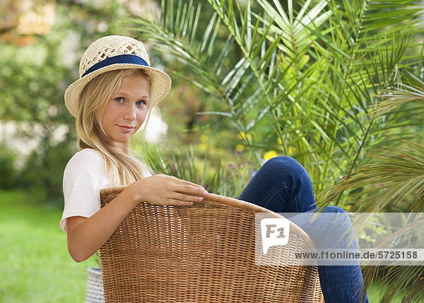 Österreich  Teenagermädchen auf Stuhl im Garten  Portrait