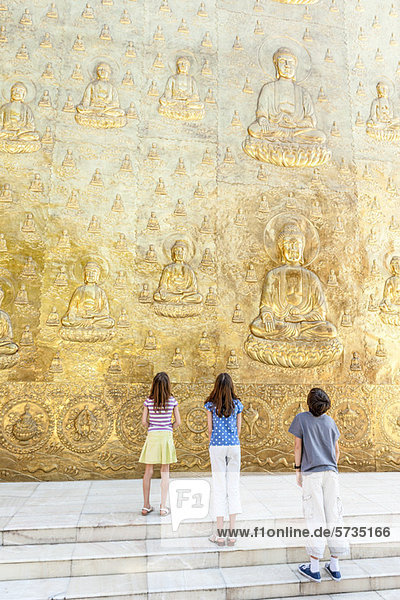 Junge Touristen schauen auf das buddhistische Flachrelief