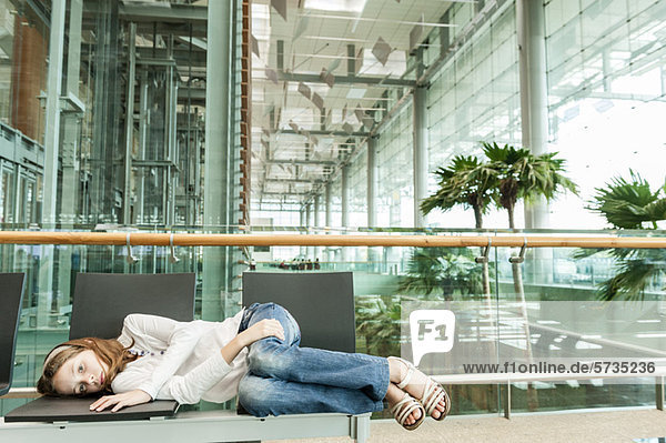 Mädchen auf Stühlen im Flughafen liegend