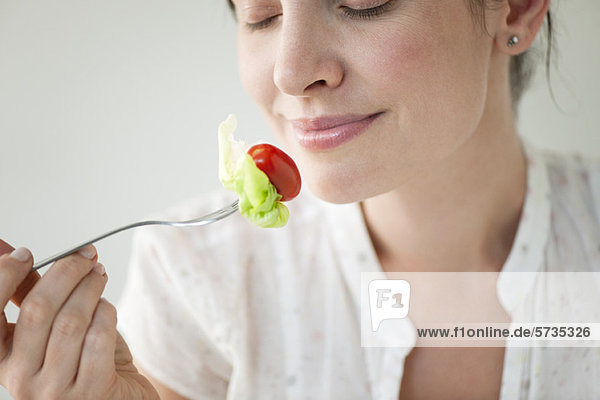 Frau im mittleren Erwachsenenalter genießt frisches Gemüse