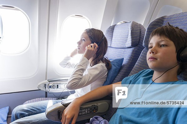Kinder sehen sich einen Film im Flugzeug mit Kopfhörer an.