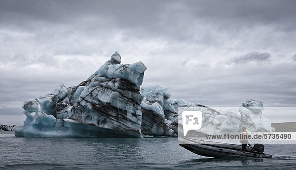 Motorboot fährt am Eisberg in der Jokulsarlon-Gletscherlagune vorbei  Island