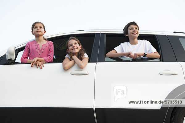 Siblings leaning out of car window  smiling  portrait