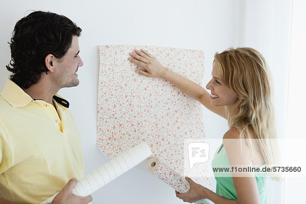 Couple decorating new house with wallpaper