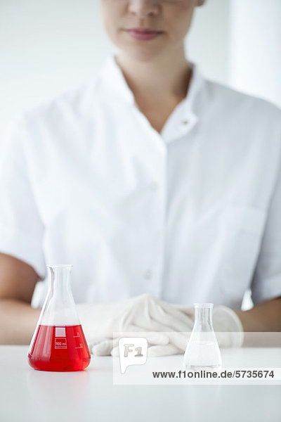 Konische Flaschen im Labor  Frau mit Latexhandschuhen im Hintergrund
