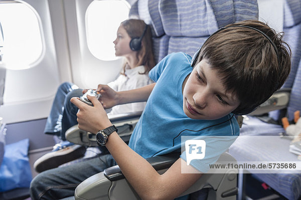 Boy leaning out of seat on airplane to look down aisle