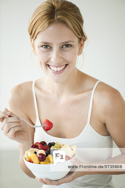 Young woman eating bowl of fruit  portrait
