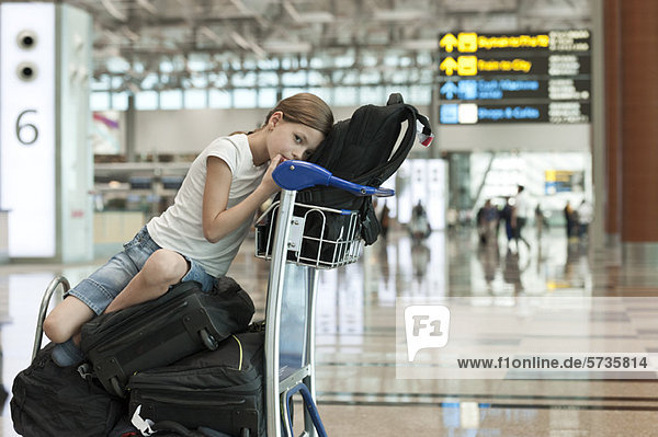 Mädchen sitzt auf dem Gepäck im Flughafen