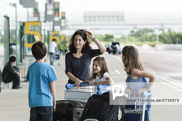 Familie steht vor dem Flughafen mit Gepäck
