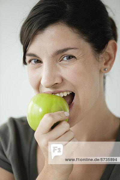 Frau im mittleren Erwachsenenalter beißt in den Apfel