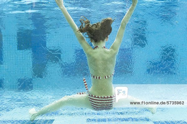 Mädchen schwimmend unter Wasser im Schwimmbad  Rückansicht