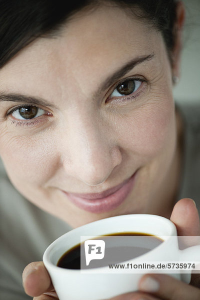 Erwachsene Frau hält eine Tasse Kaffee.