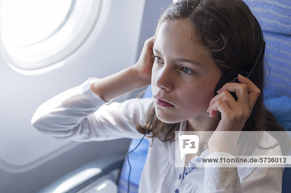 Mädchen beim Musikhören im Flugzeug mit Kopfhörer