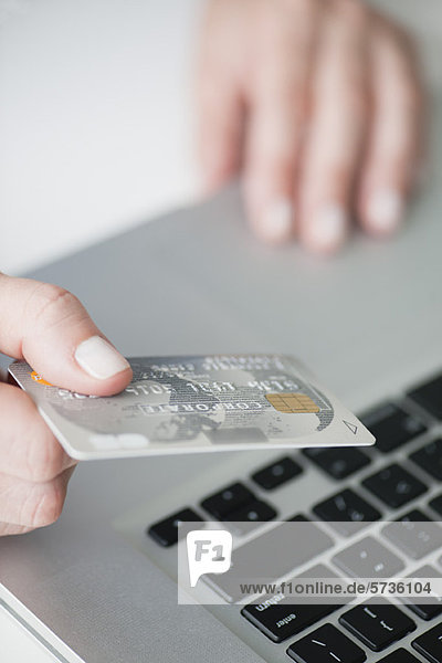 Woman holding credit card above laptop keyboard