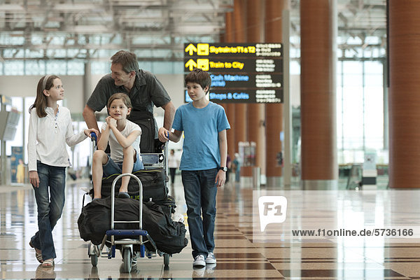 Family pushing luggage cart in airport