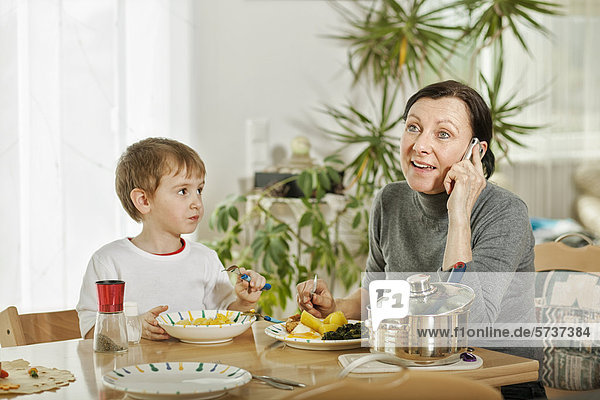 Telefonierende Mutter und Sohn beim Essen