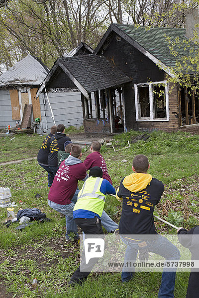 Student volunteers from the University of Michigan use a low tech approach to demolish one of the thousands of abandoned houses in the city  Detroit  Michigan  USA