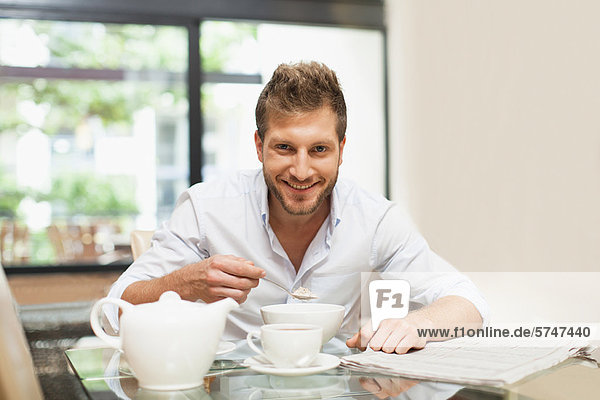 Smiling man eating breakfast at table