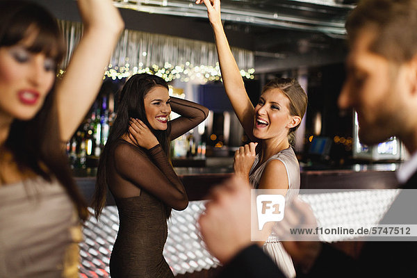 Lächelnde Freunde tanzen in der Bar