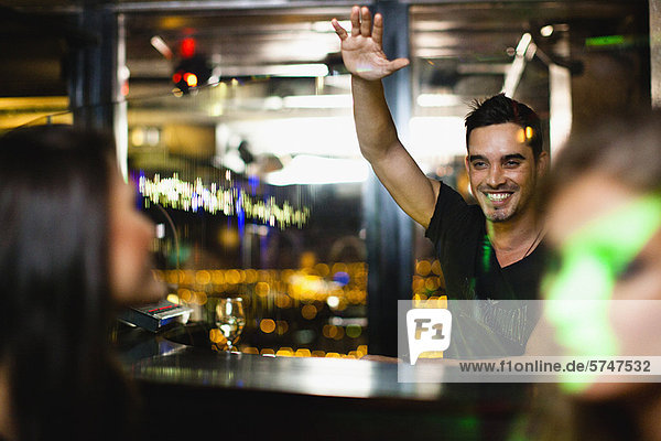 Bartender waving to customers in bar
