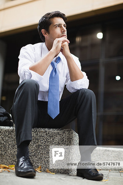 Businessman sitting on city street