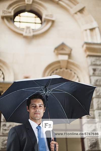 Businessman carrying umbrella on street