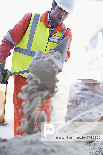Worker shoveling concrete on site