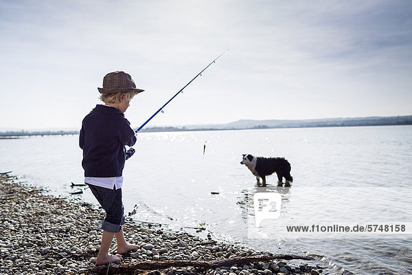 Boy fishing with dog in creek