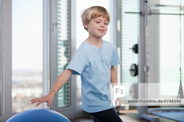 Boy playing with exercise ball in gym