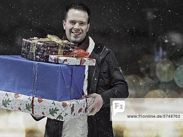 Mann mit Weihnachtsgeschenken im Schnee