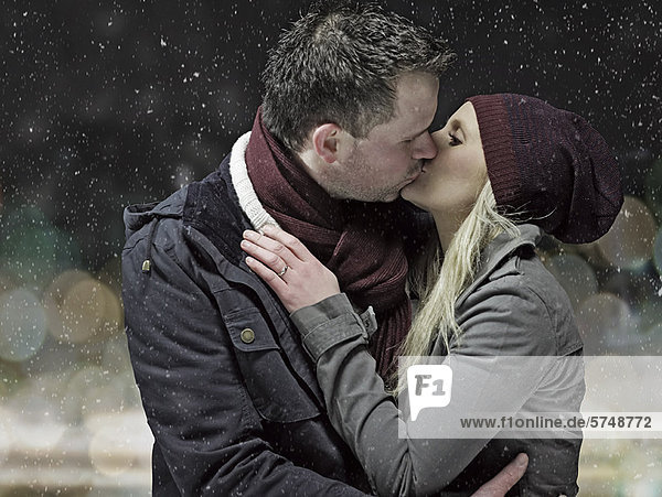 Couple kissing in snow at night