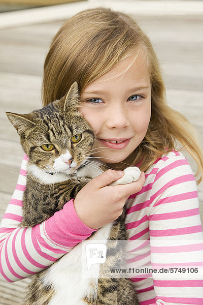 Lächelndes Mädchen hält Katze im Freien