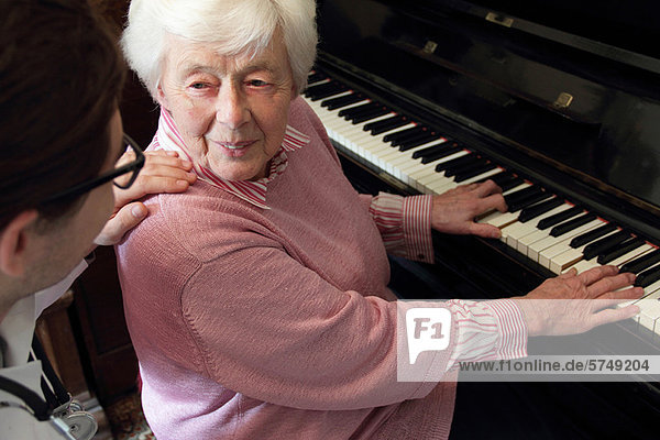 Arzt beobachtet ältere Frau beim Klavierspielen