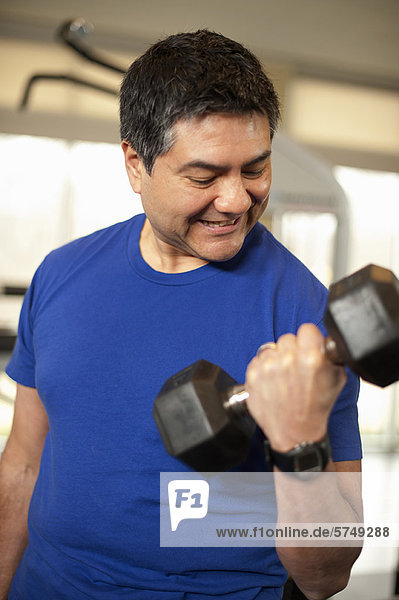 Smiling man lifting weights in gym