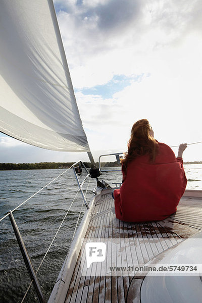 Woman sitting on bow of yacht