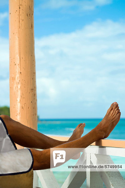 Mann im Urlaub mit Beinen auf der Verandaschiene