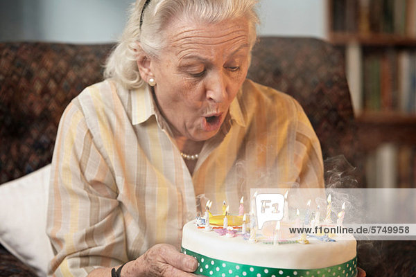 Seniorin beim Ausblasen von Geburtstagskerzen