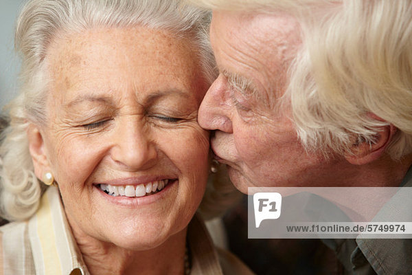 Senior Mann küsst Seniorin auf Wange
