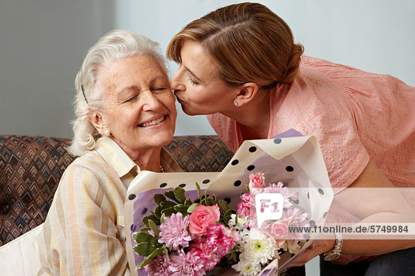 Daughter giving senior mother bouquet of flowers