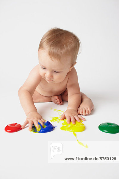Baby legt Hände in Fingerfarben