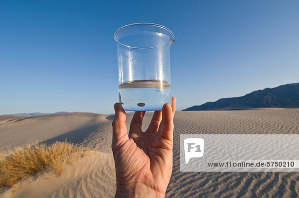 Mann hält Wasser im Becherglas im Death Valley National Park  Kalifornien  USA