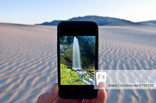 Mann hält Handy mit Wasserfallbild im Death Valley National Park Kalifornien USA