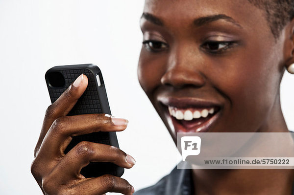 Junge Frau hält Handy vor weißem Hintergrund