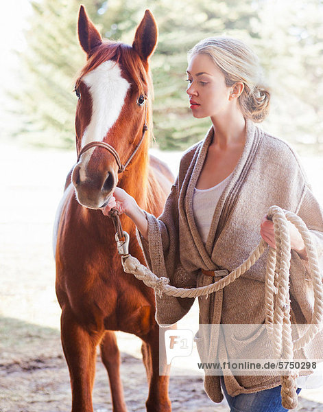Junge Frau auf der Suche nach Pferd auf Bauernhof