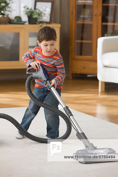 Boy using vacuum cleaner on rug