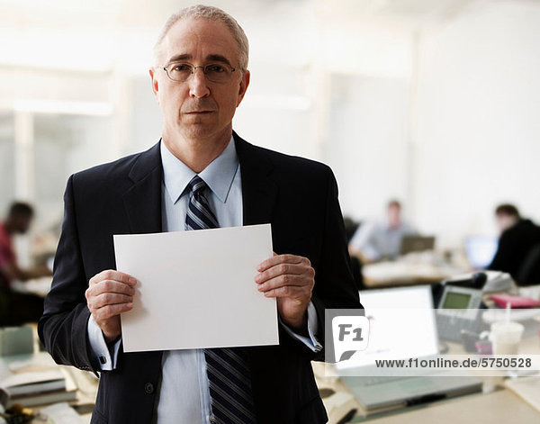Portrait of senior man holding blank sheet of paper