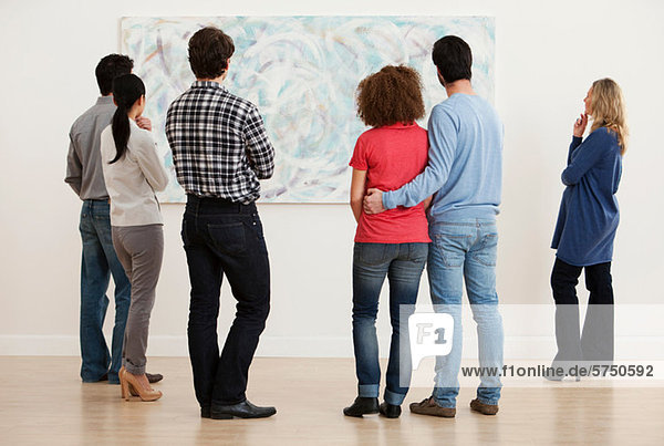 Men and women looking at oil painting in art gallery